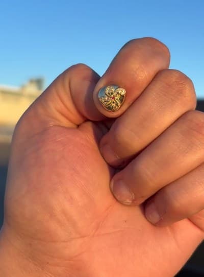 Carved gold signet ring with a red stone worn on a fist